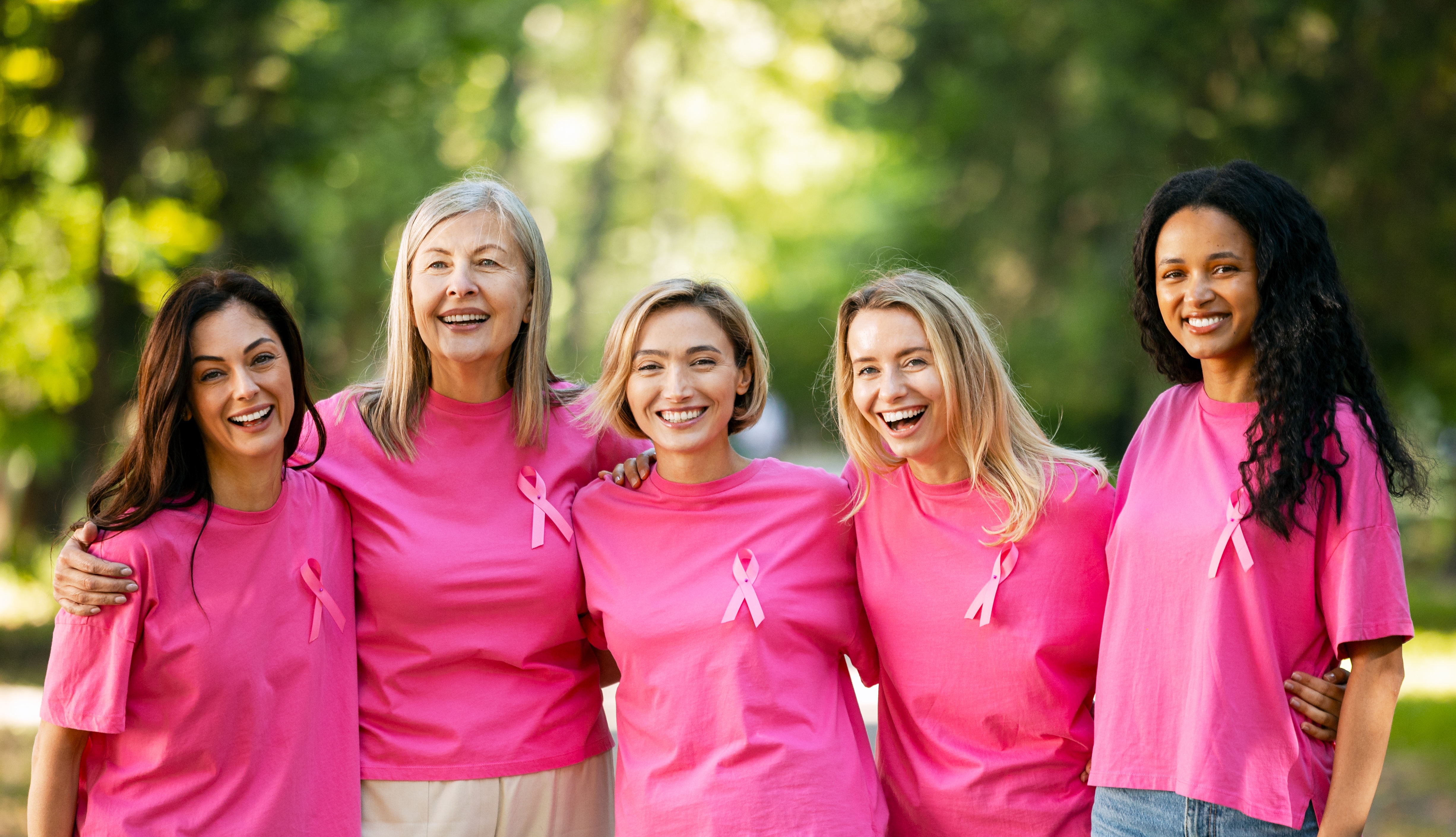 Five women wearing pink shirts and pink ribbons