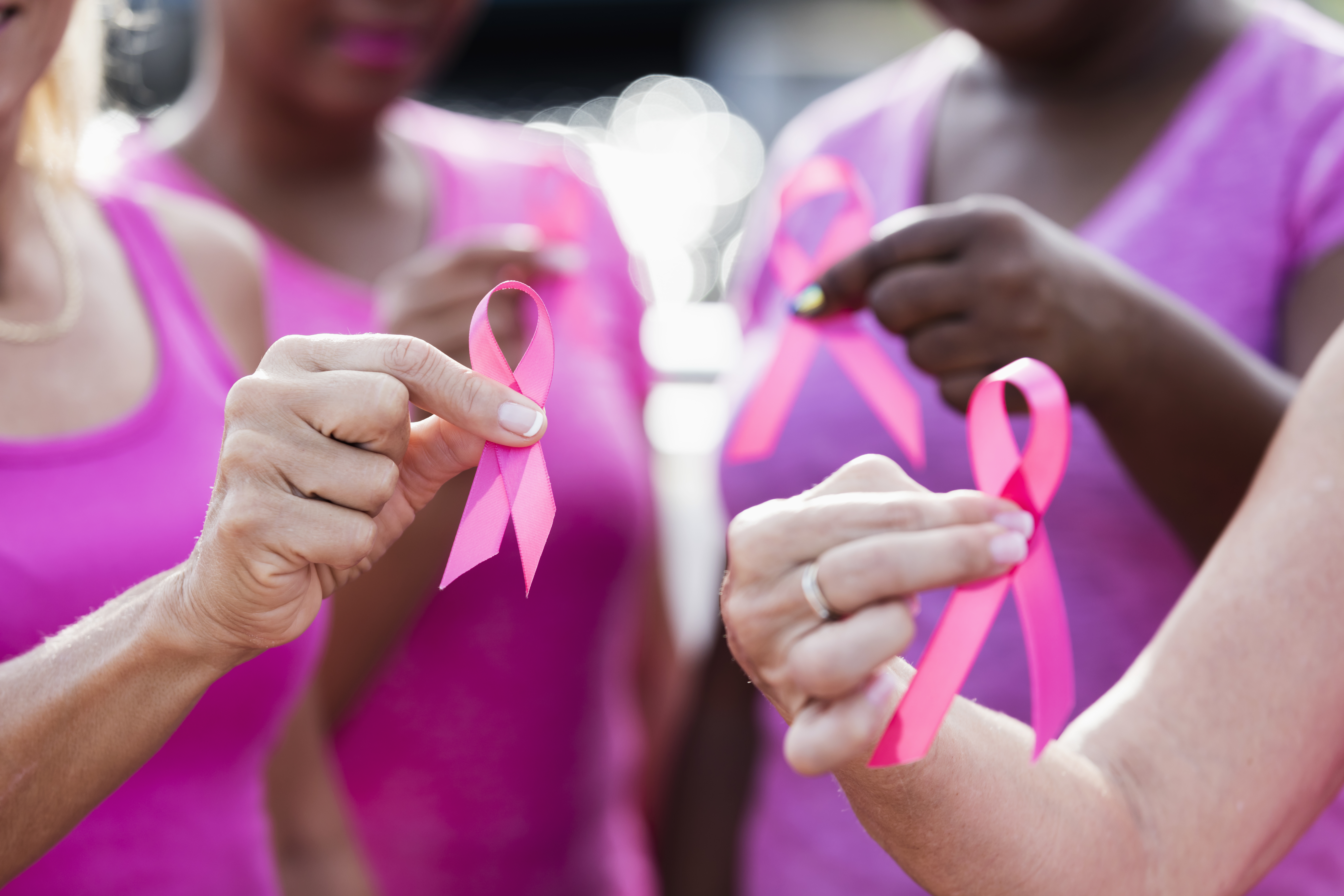 Women wearing pink shirts and holding pink ribbons